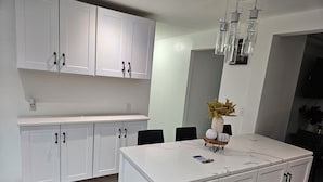 Une cuisine moderne avec des meubles blancs, un plan de travail en marbre et un îlot central.