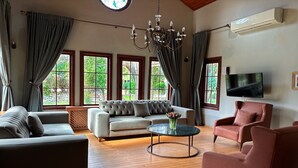Uma sala de estar com sofá, poltronas, mesa de centro e televisão.