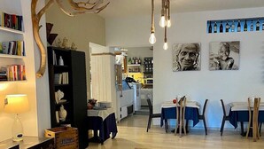 Zona pranzo con un lampadario rustico, una libreria e una parete decorata con opere d'arte.