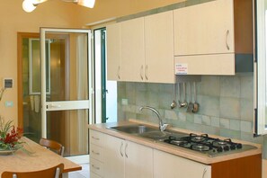 Een keuken met een gasfornuis, spoelbak en kastjes.