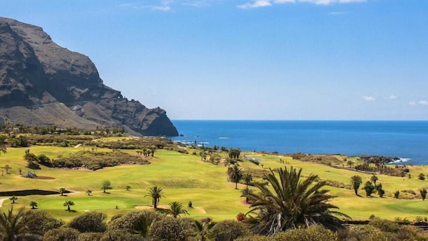 A coastal landscape with a golf course, a mountain, and the ocean. - Finca El Castillo (Buenavista del Norte)