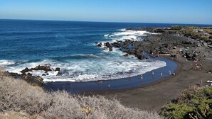 A beach with dark sand, rocky shoreline, and clear blue water. - Finca El Castillo (Buenavista del Norte)