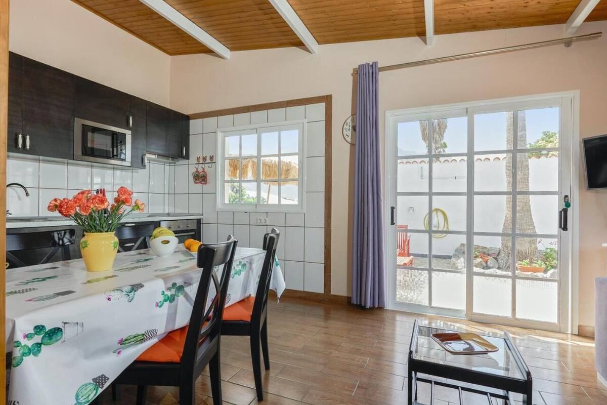 A modern kitchen with dark cabinets, a microwave, and a dining area with a table set for two.