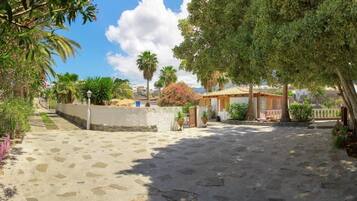 Un patio empedrado con suelo de piedra, rodeado de árboles y un pequeño edificio con tejado de tejas.
