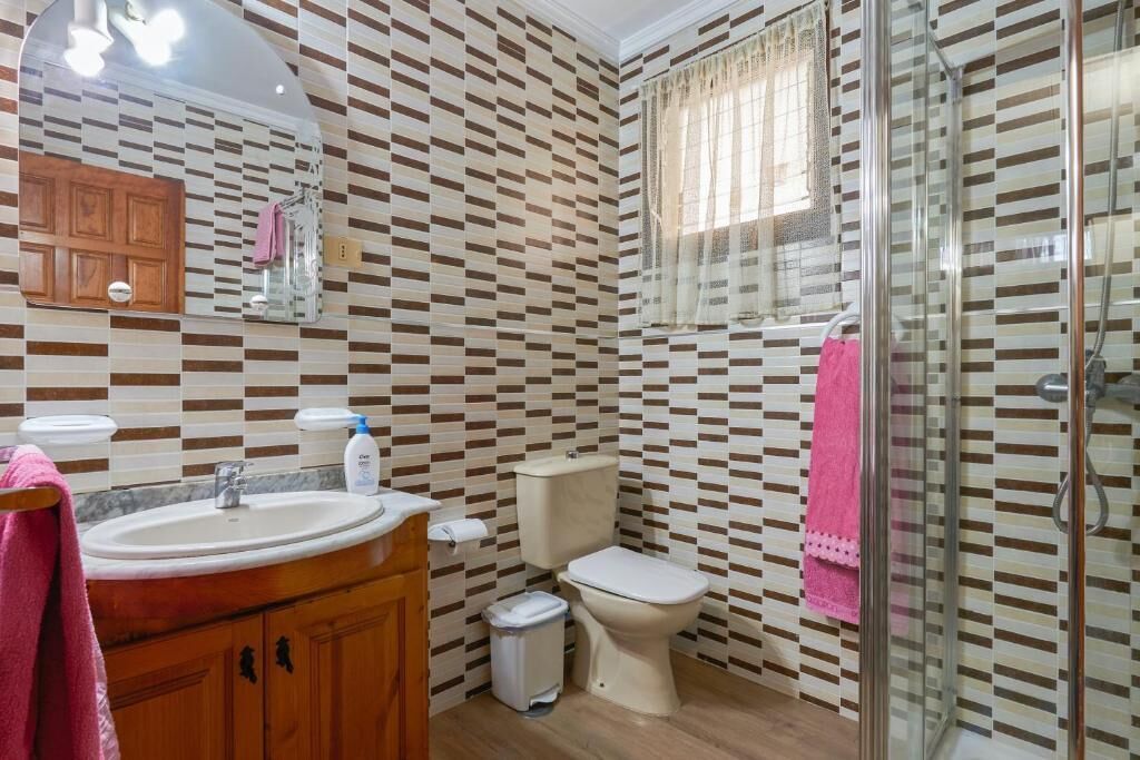 Un bagno con parete decorata, lavandino, water e box doccia in vetro.