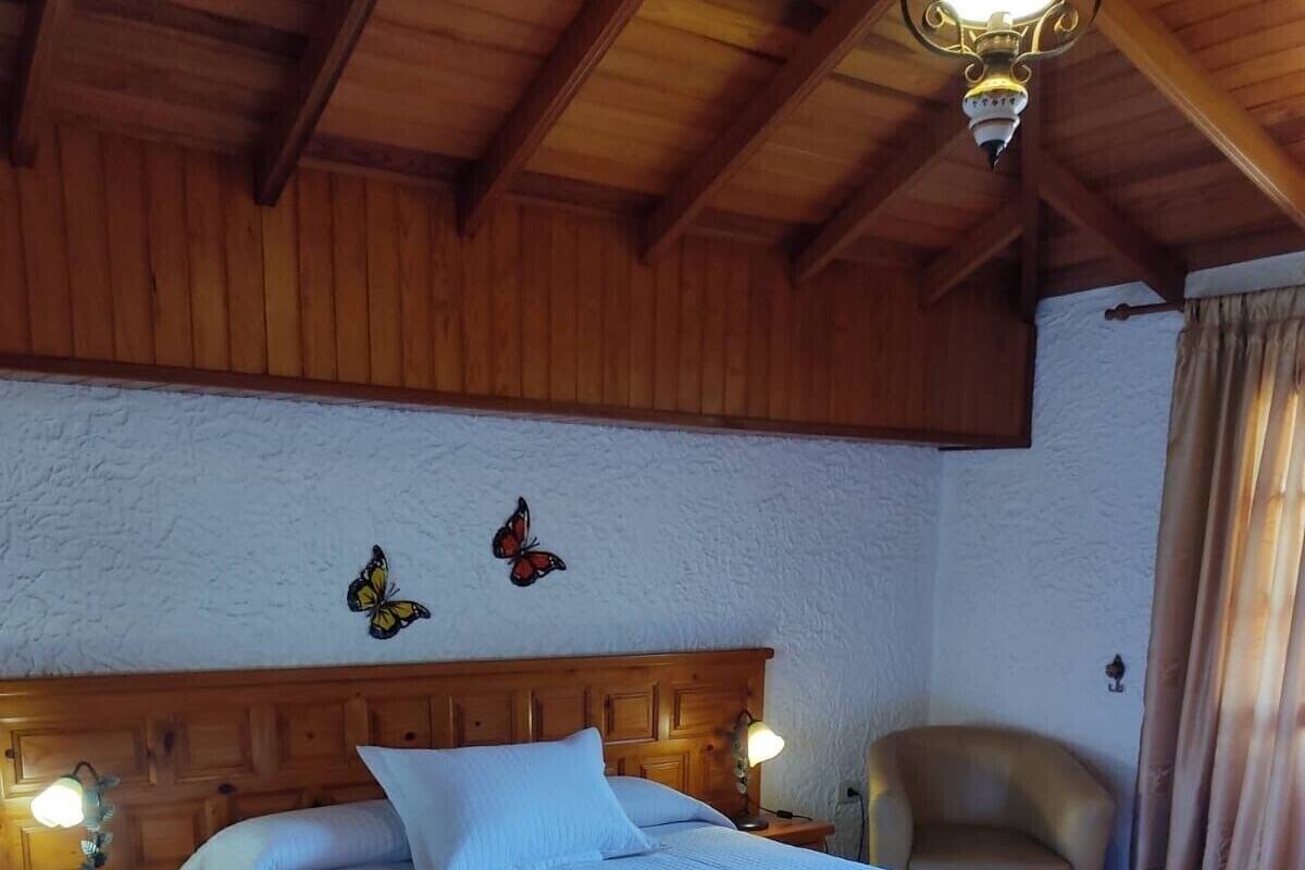 A bedroom with a wooden headboard, a bed with white bedding, two wall-mounted lamps, and a butterfly decoration.