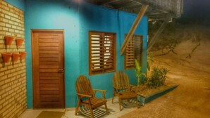 Un petit bâtiment accueillant, à la façade bleue, avec une porte en bois et deux chaises en bois à l’extérieur.