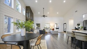 A spacious kitchen with a dining area, large windows, and a ceiling fan. - Romantic Luxury Modern Cabin/Patio Oasis Hot Tub! (Broken Bow)