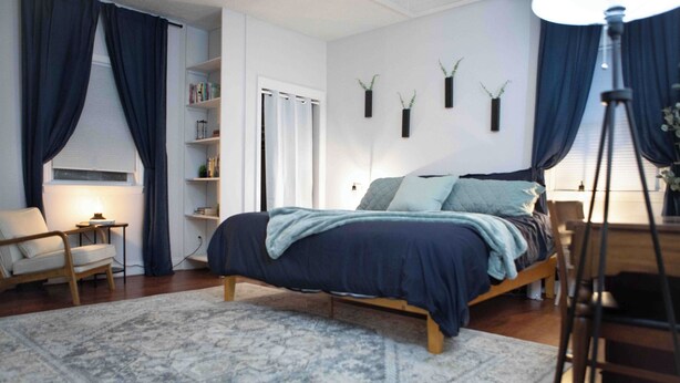 Une chambre à coucher avec un lit, une chaise, une bibliothèque et une lampe.