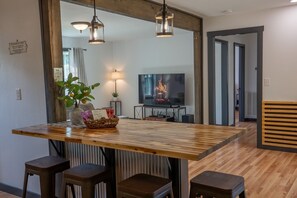 Ein moderner Essbereich mit Holztisch, Barhocker, Fernseher und Kamin.