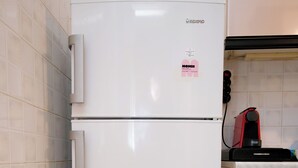 A white refrigerator with a sticker, a red appliance on the counter, and beige cabinets. - Olga's  Lovely  Elia  Apartment  -  Kaisariani (Athina)