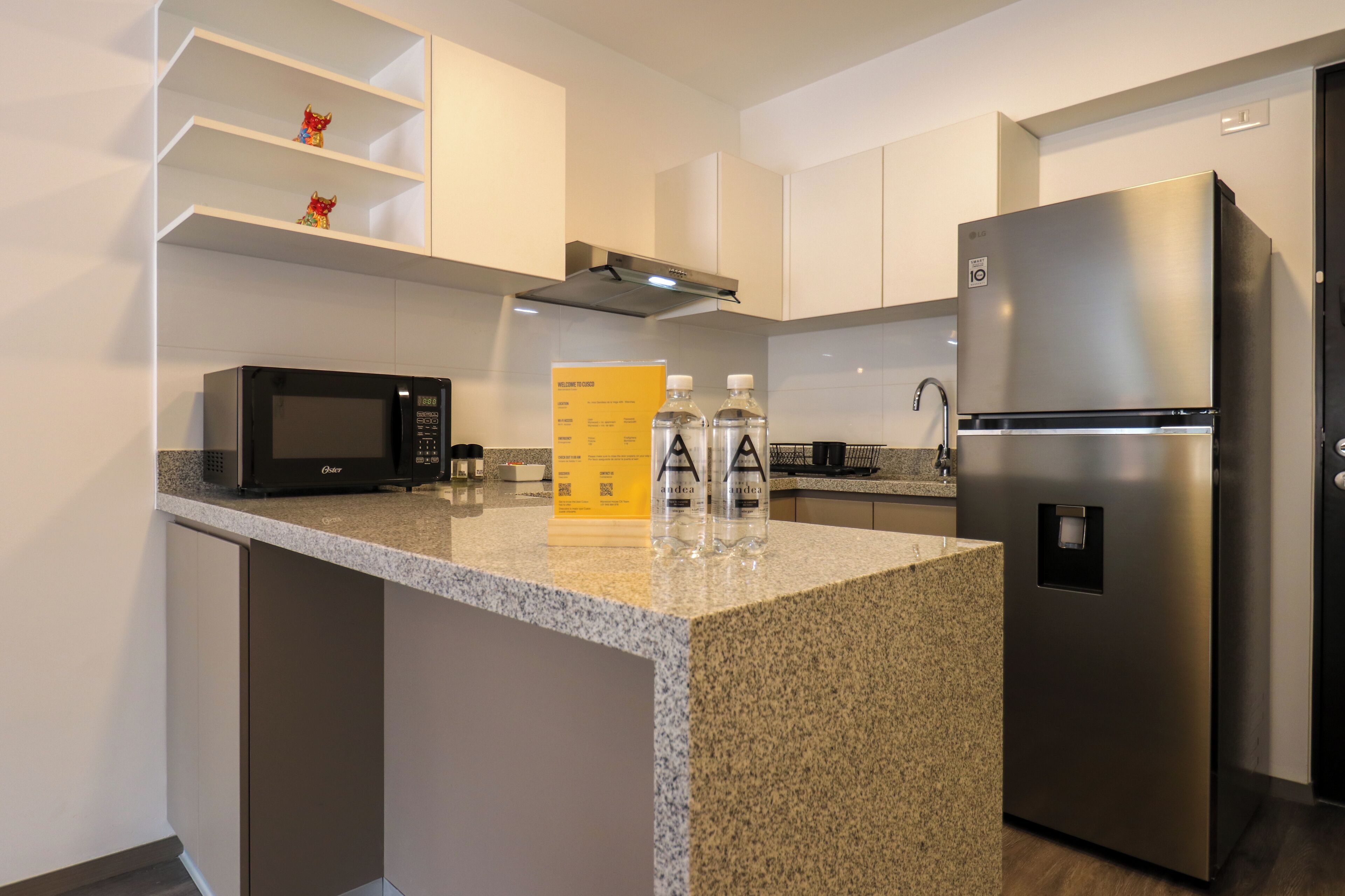 Una cocina moderna con encimera de granito, electrodomésticos de acero inoxidable y armarios blancos.