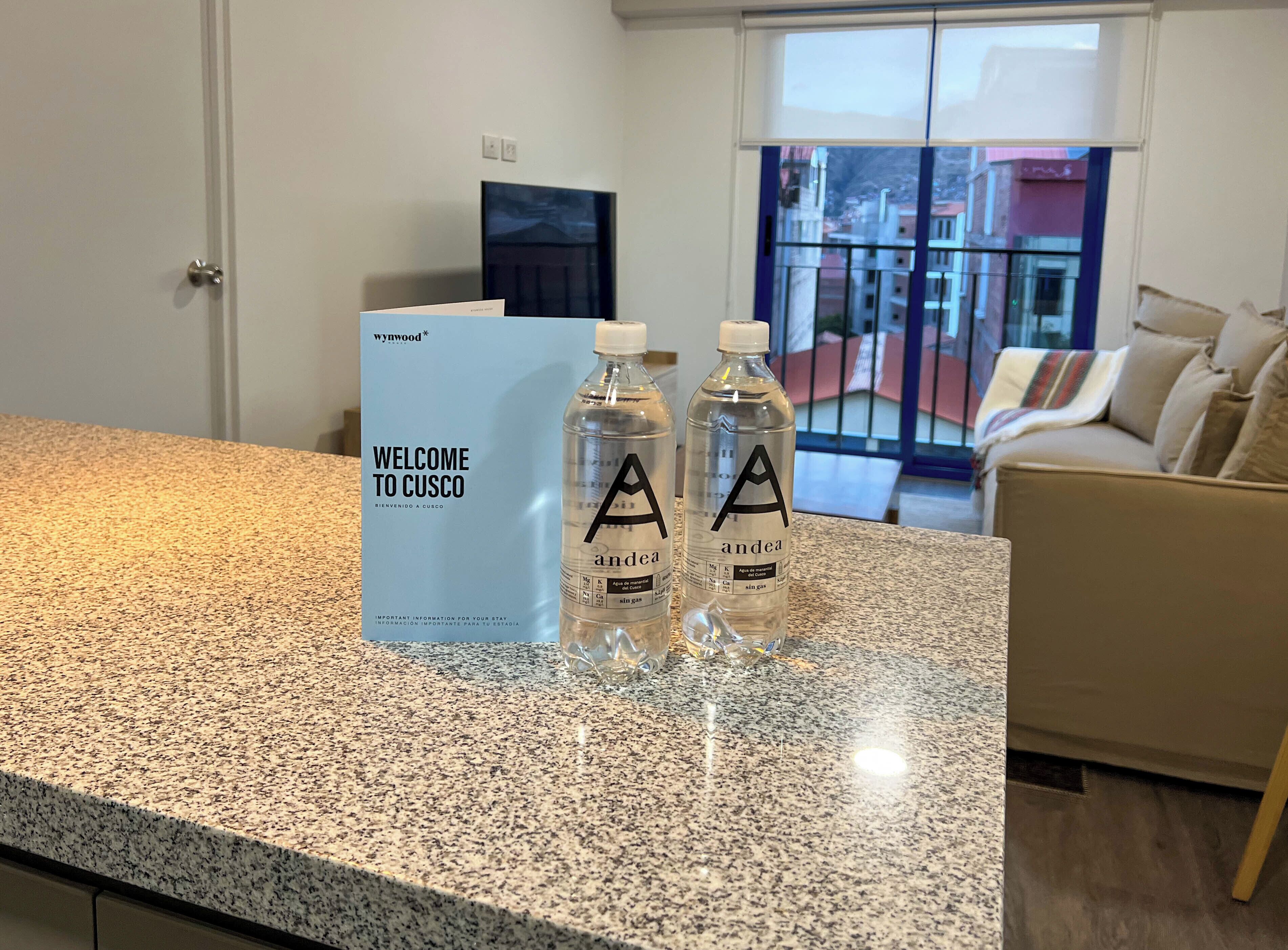 A reception desk with a welcome sign, two water bottles, and a view of the outside through a window.