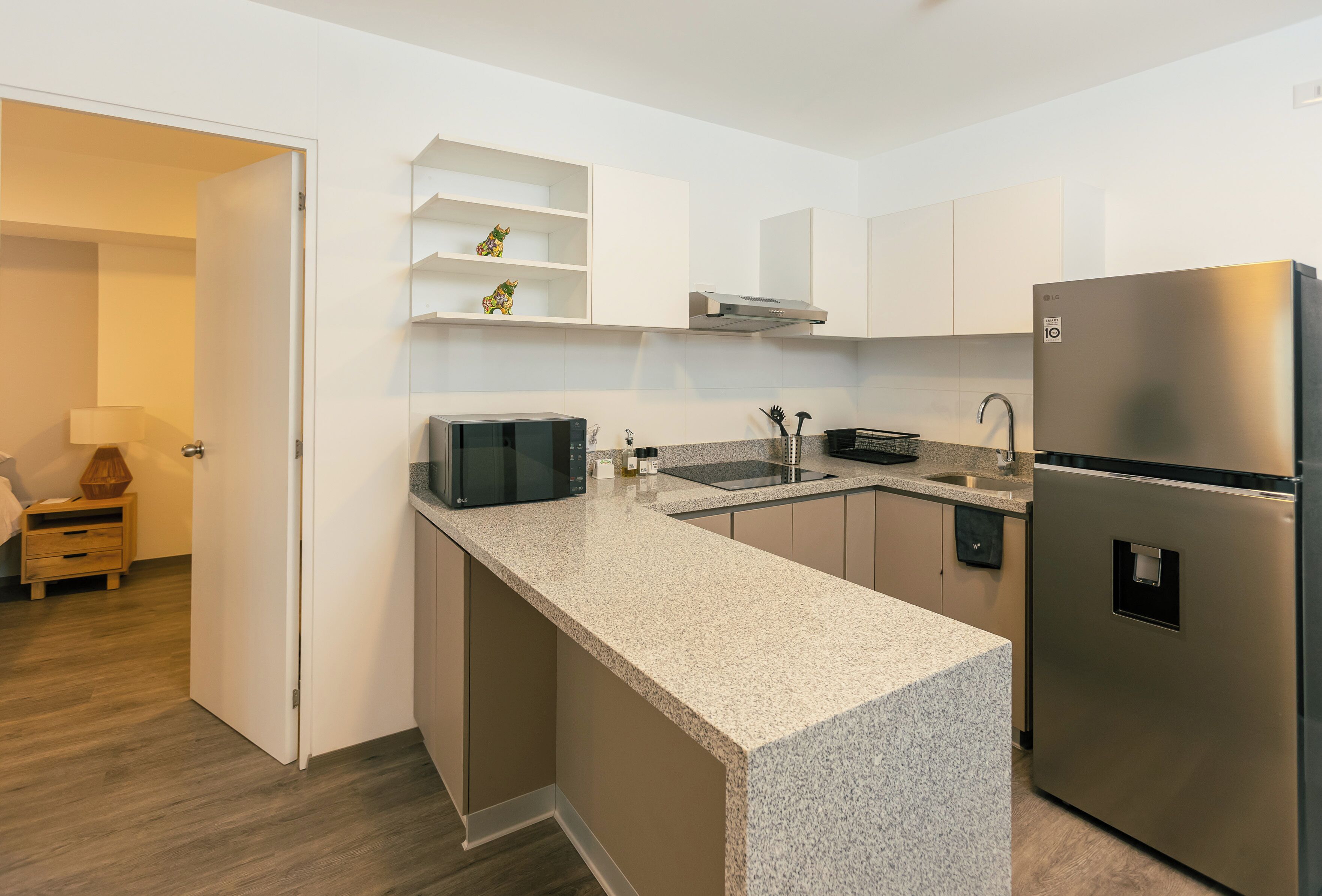 A modern kitchen with a granite countertop, stainless steel appliances, and white cabinetry.