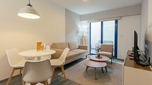 Una sala de estar moderna con una mesa de comedor redonda, un sofá y un televisor.