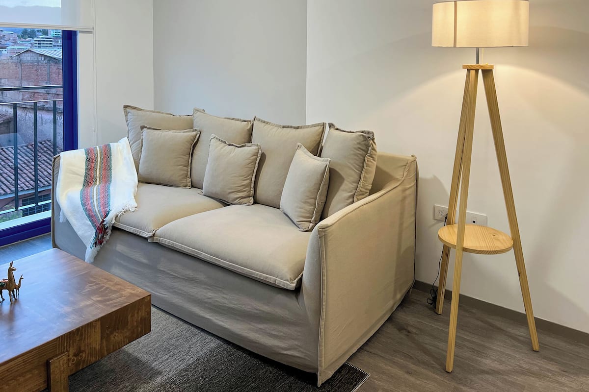 Una sala de estar moderna con un sofá color beige, una mesa de centro de madera y una lámpara de pie.