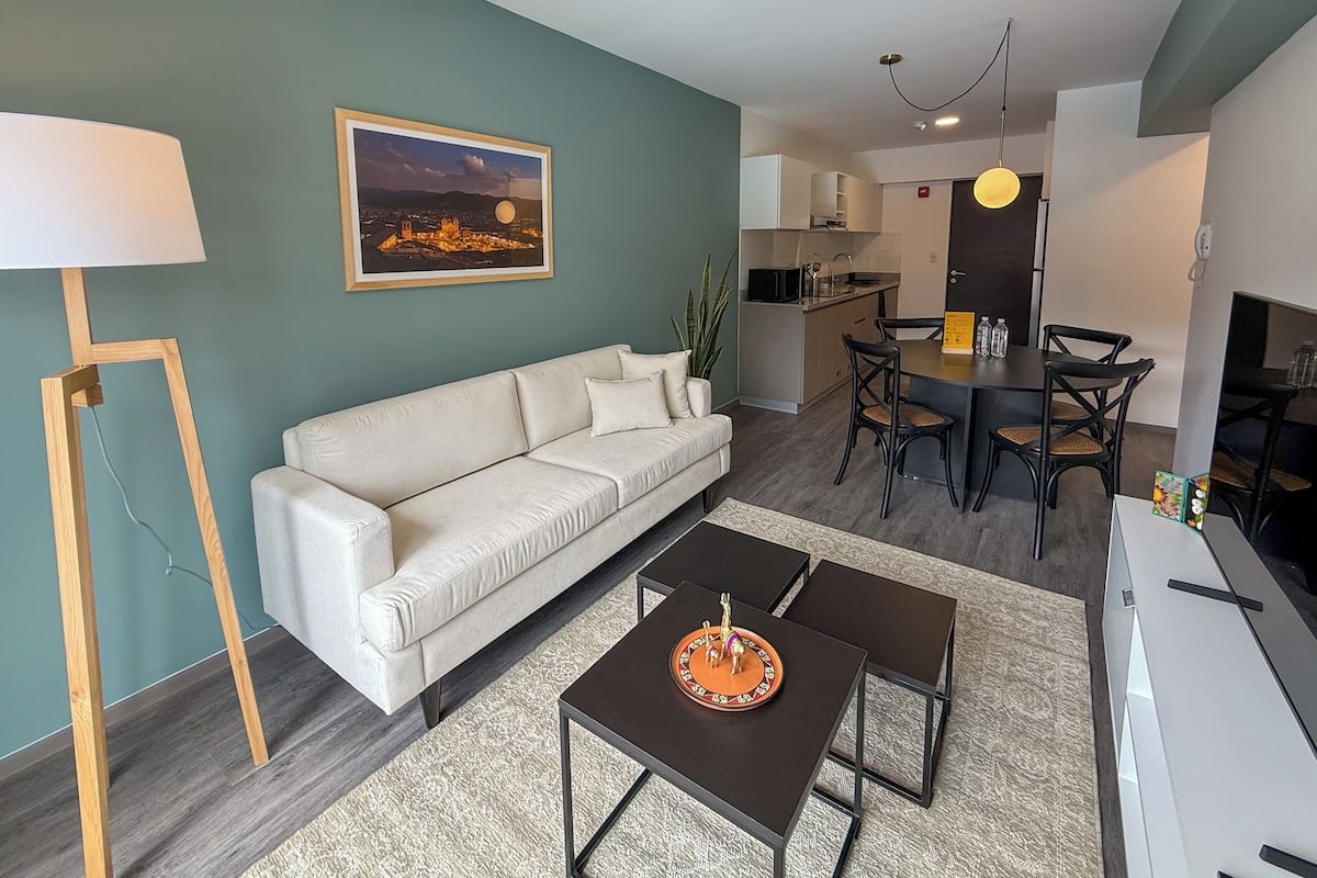 Una sala de estar moderna con sofá, mesa de centro y zona de comedor con sillas y una mesa.