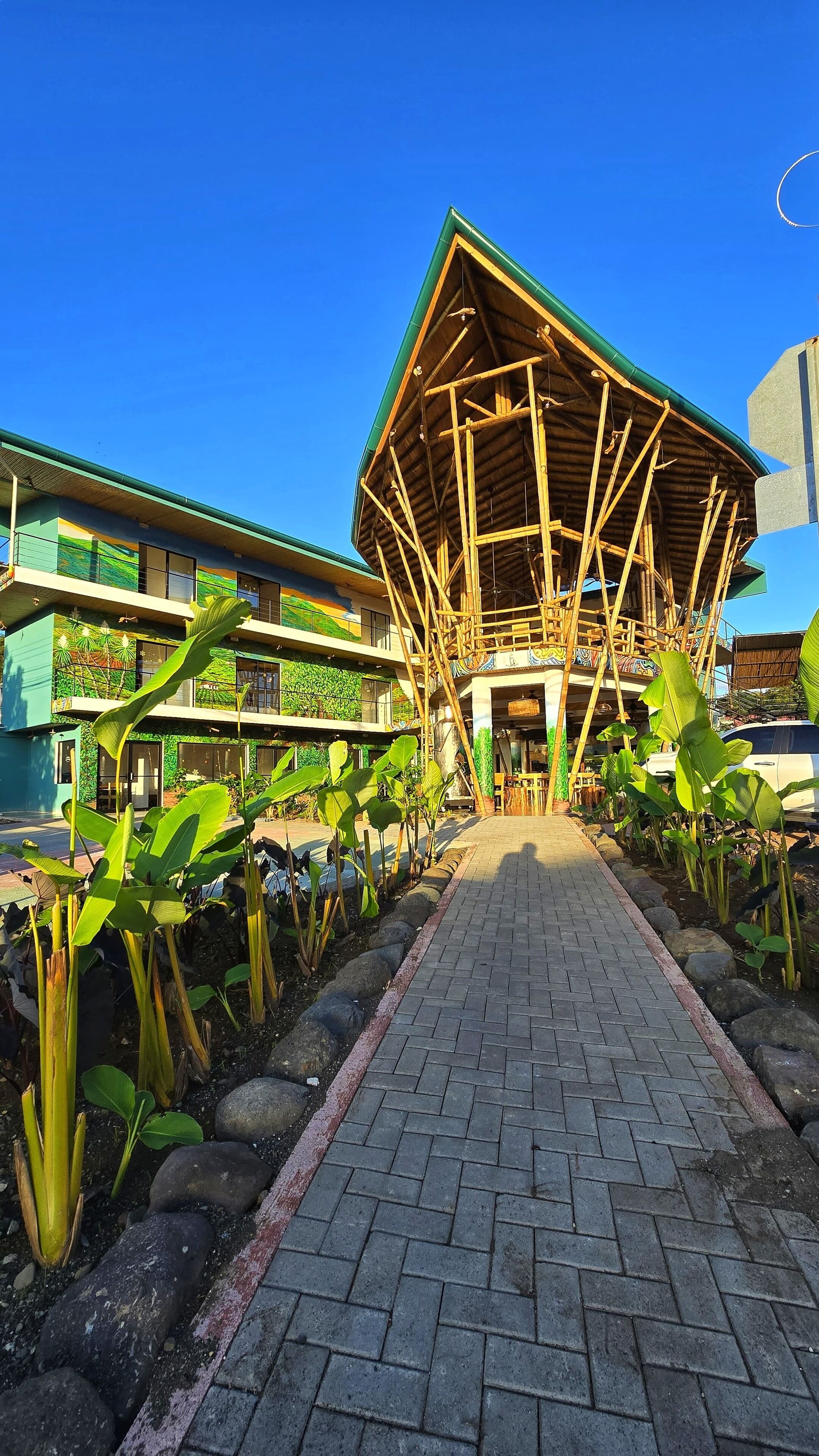 A building with a bamboo structure and a paved walkway.