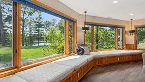 Une pièce dotée de grandes fenêtres, d’une banquette intégrée avec des coussins et d’un luminaire suspendu.