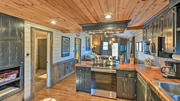 A spacious kitchen with wooden ceiling, stainless steel appliances, and a central island.