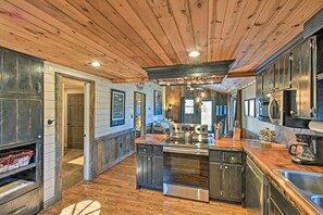 A spacious kitchen with wooden ceiling, stainless steel appliances, and a central island.