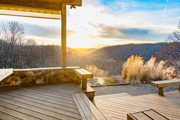 A wooden deck with benches overlooking a mountainous landscape.