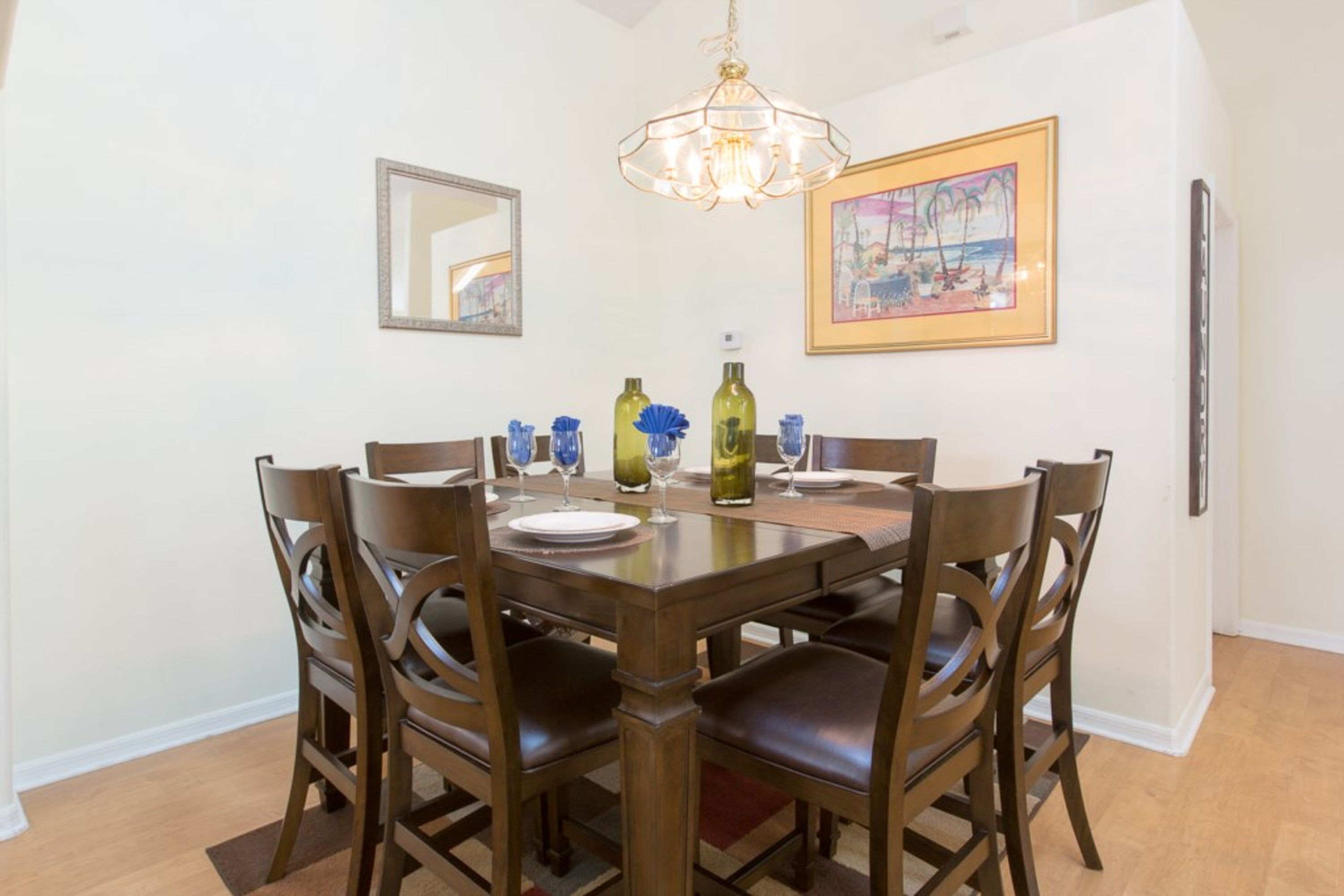 Un coin repas avec une table et des chaises en bois, un lustre et un tableau encadré au mur.