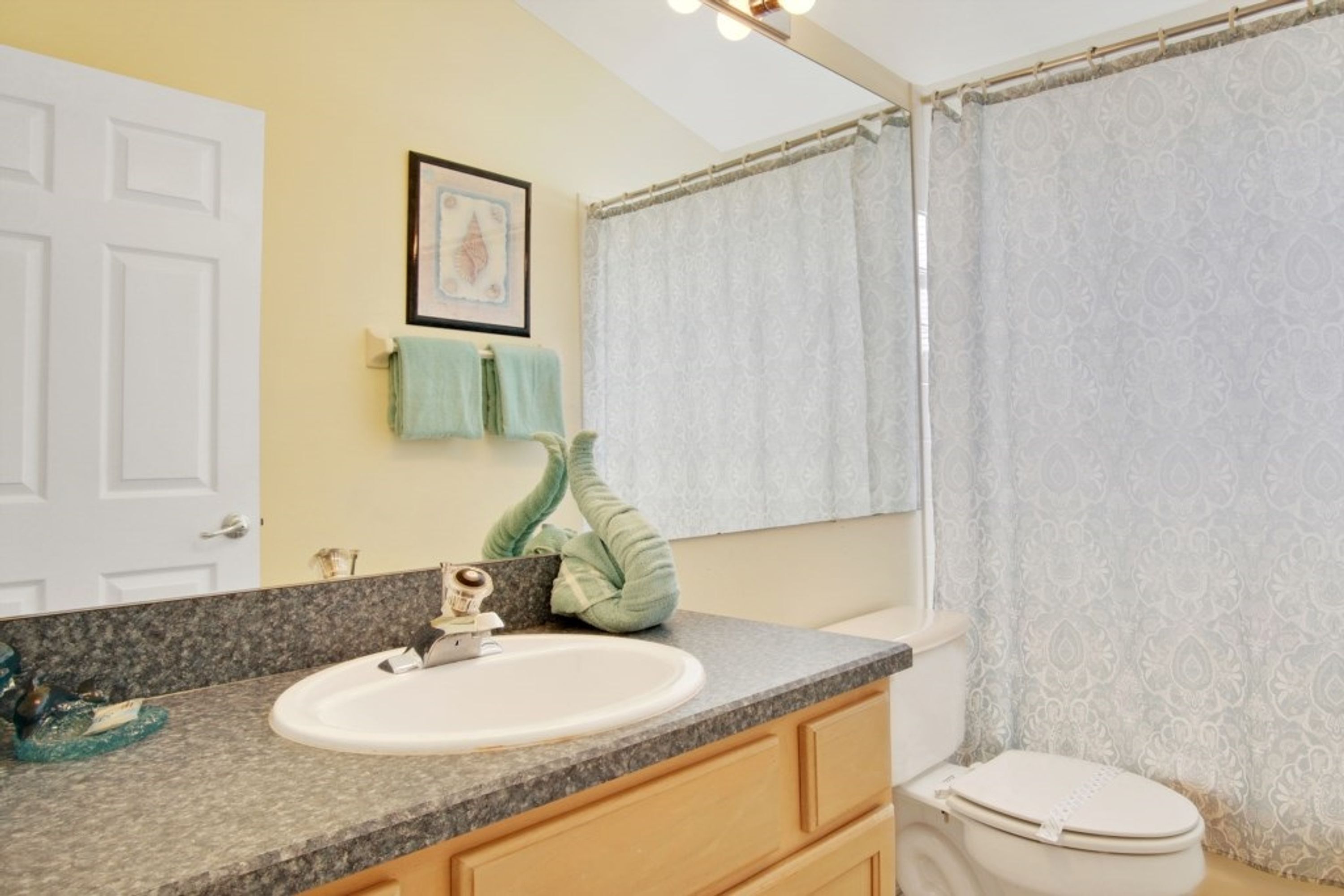 A bathroom with a white sink, a toilet, and a shower curtain.
