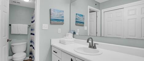 A bathroom with a white sink, a mirror with lights, and a toilet.