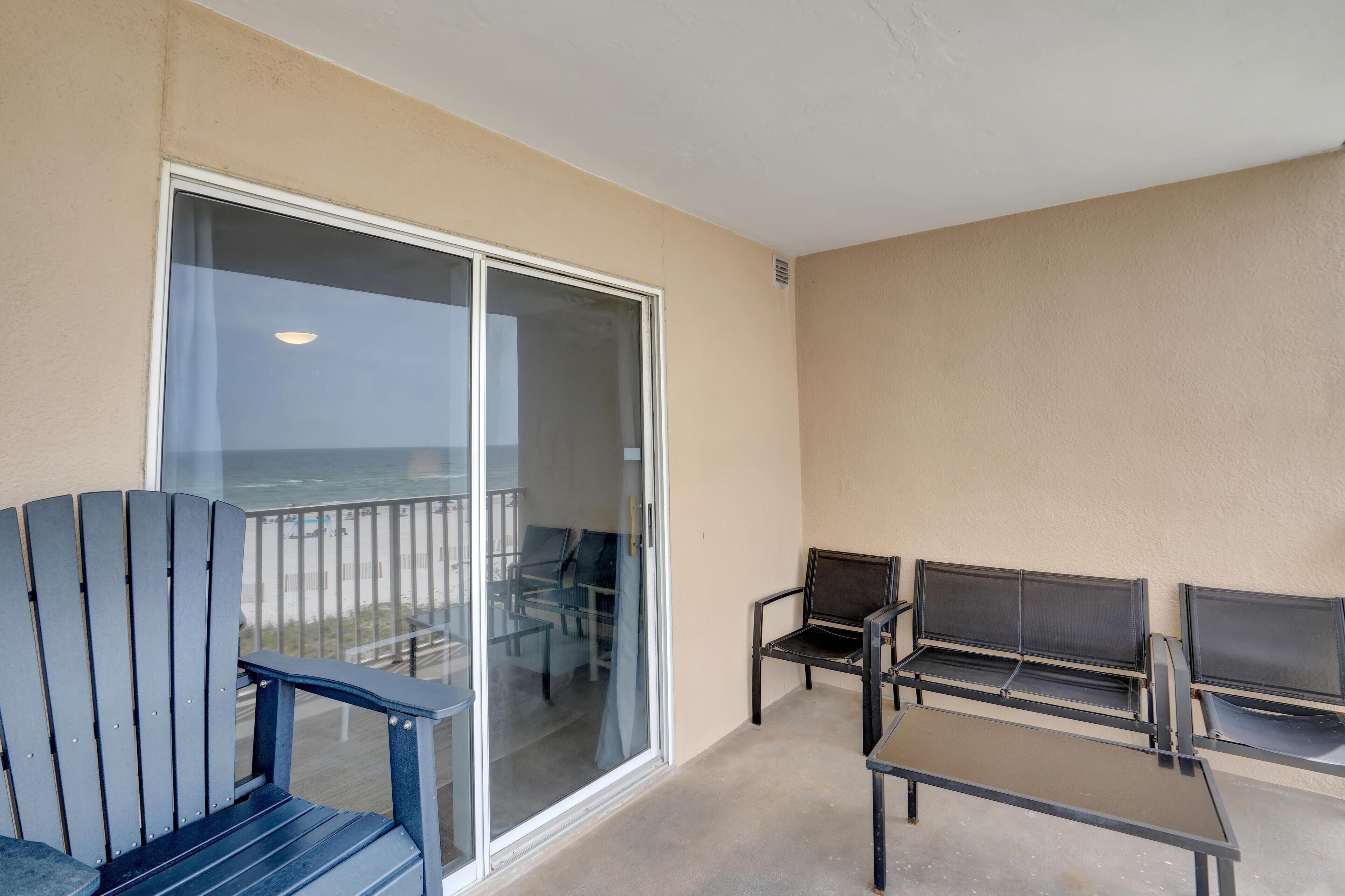 A balcony with a glass door, two chairs, and a table.