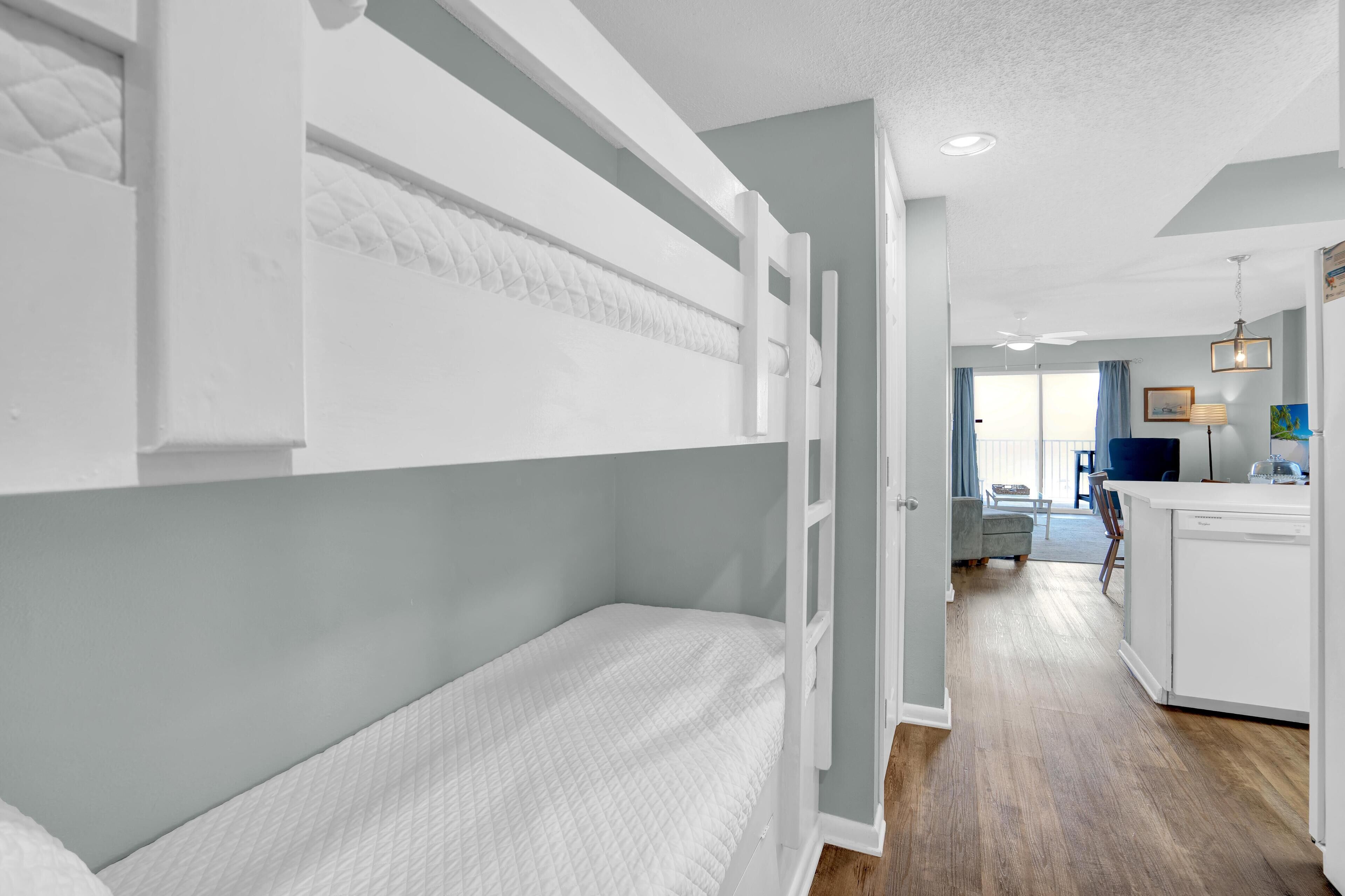 A modern hotel room with bunk beds, a kitchenette, and a view of the living area.