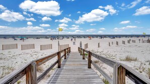 A wooden boardwalk leading to a sandy beach with umbrellas and beachgoers. - Four Winds 304 (Orange Beach)