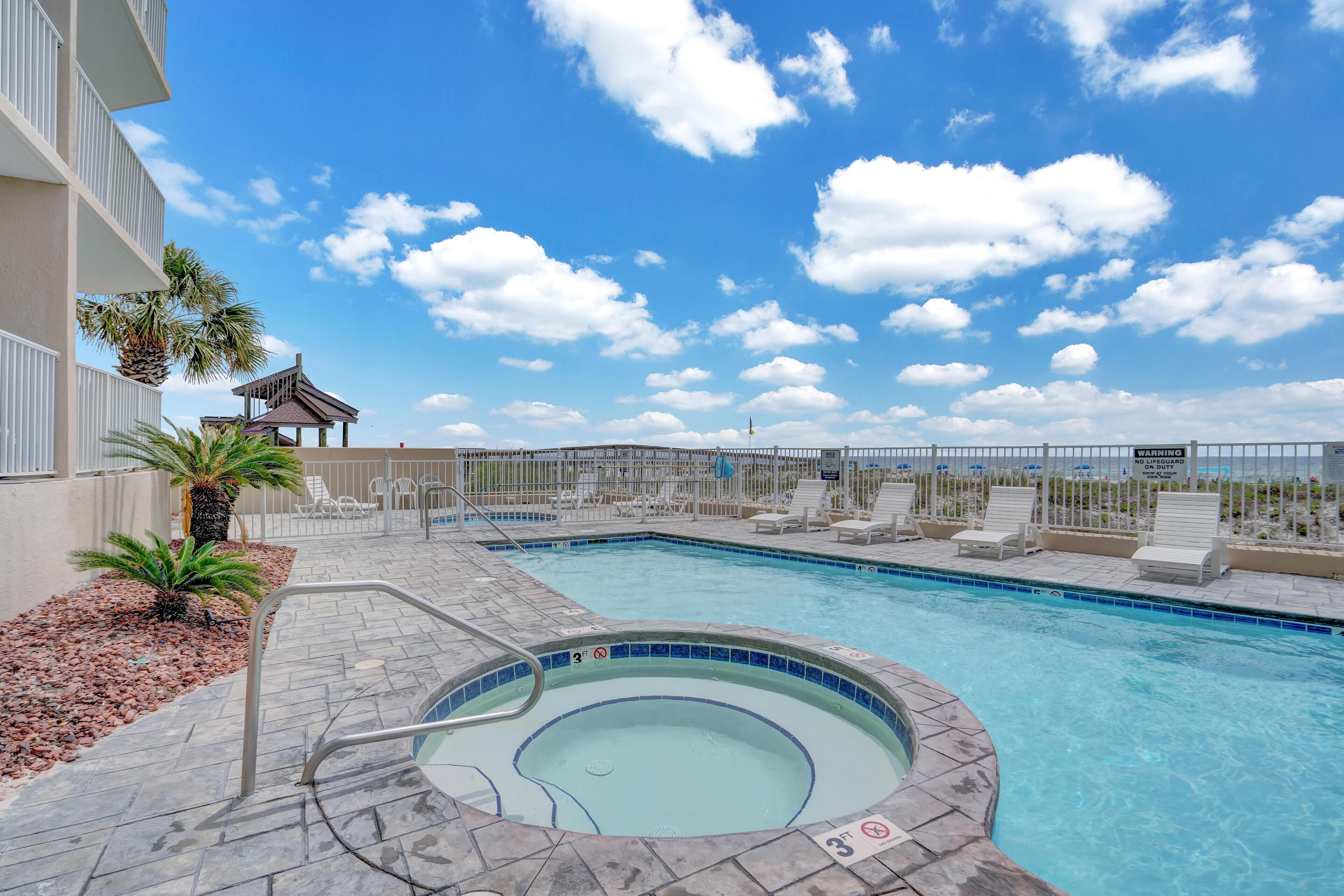 Une piscine avec un jacuzzi, des chaises longues et un palmier.
