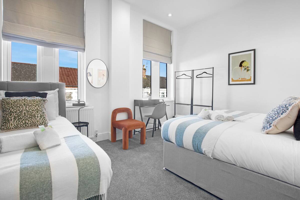 Une chambre d’hôtel moderne avec deux lits, un bureau et une chaise.