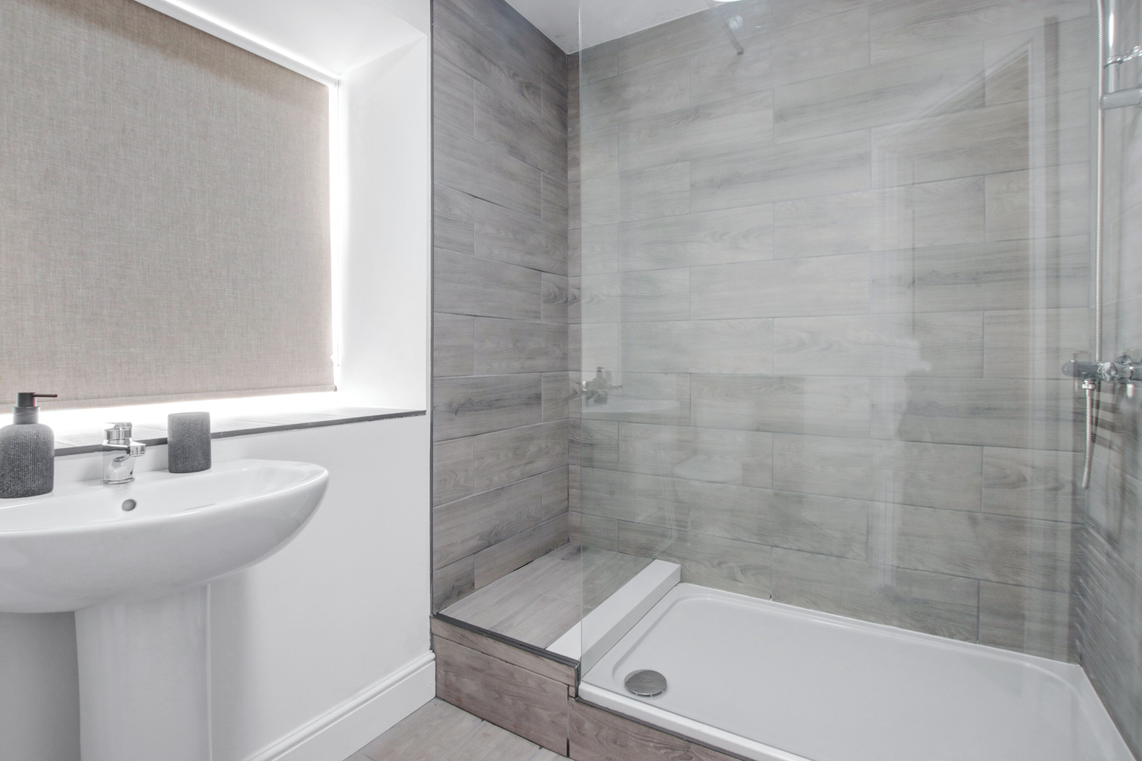 A modern bathroom with a white sink, a glass shower enclosure, and a built-in bathtub.