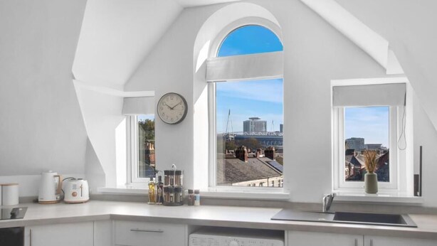A modern kitchen with a large window, a clock, and a view of a cityscape.