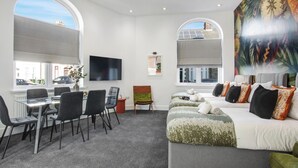 A modern hotel room with a dining area, large windows, and a mural.