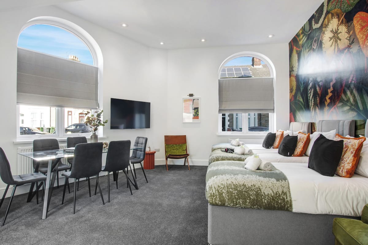 Une chambre d’hôtel moderne dotée d’un coin repas, de grandes fenêtres et d’une fresque murale.