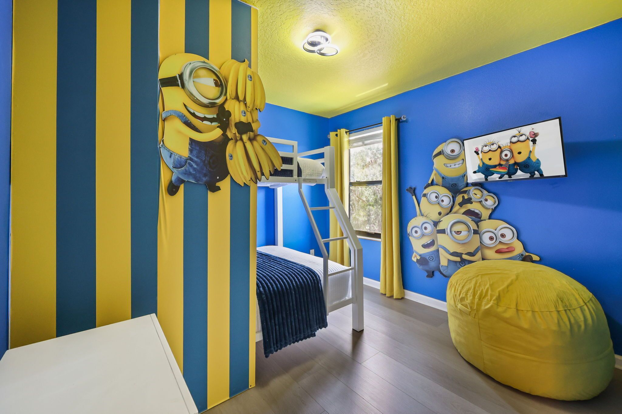 A bunk bed with a ladder, a yellow bean bag, and Minion-themed decorations.