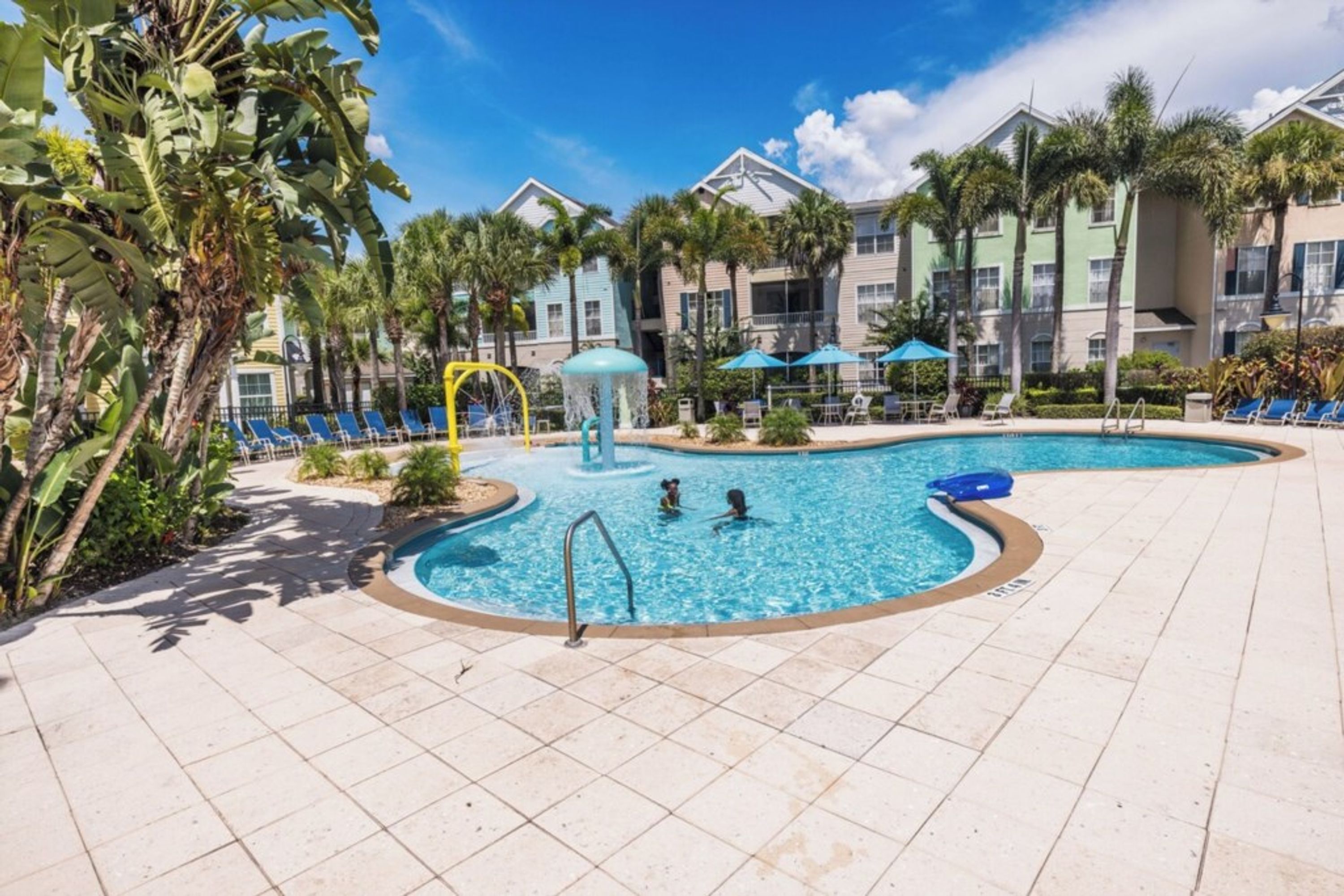A pool area with a diving board, lounge chairs, and a water slide.
