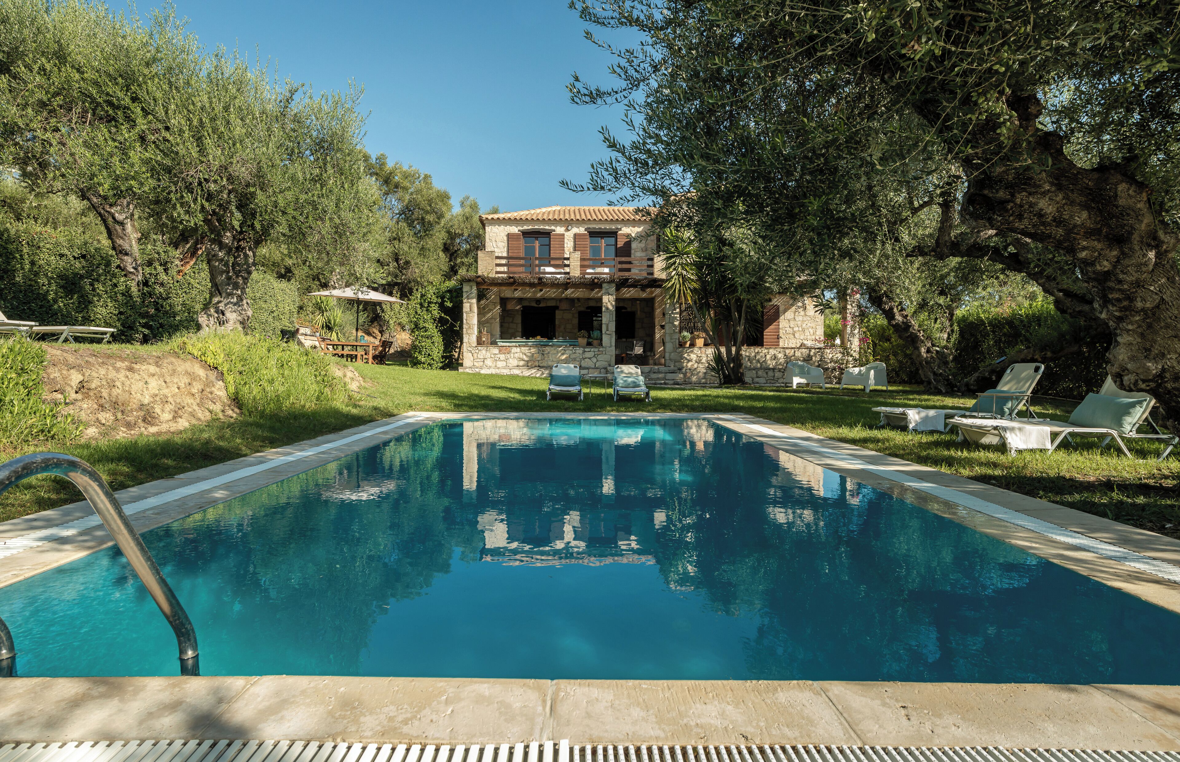 A swimming pool with lounge chairs and a stone building in the background.