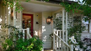 A house with a porch, a red door, and a staircase leading to the entrance.