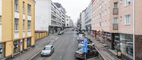 A street with parked cars, buildings, and a pedestrian crossing.
