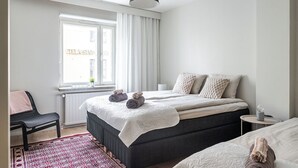 Un dormitorio moderno con una cama grande, una mesita de noche, una silla y una ventana con cortinas.