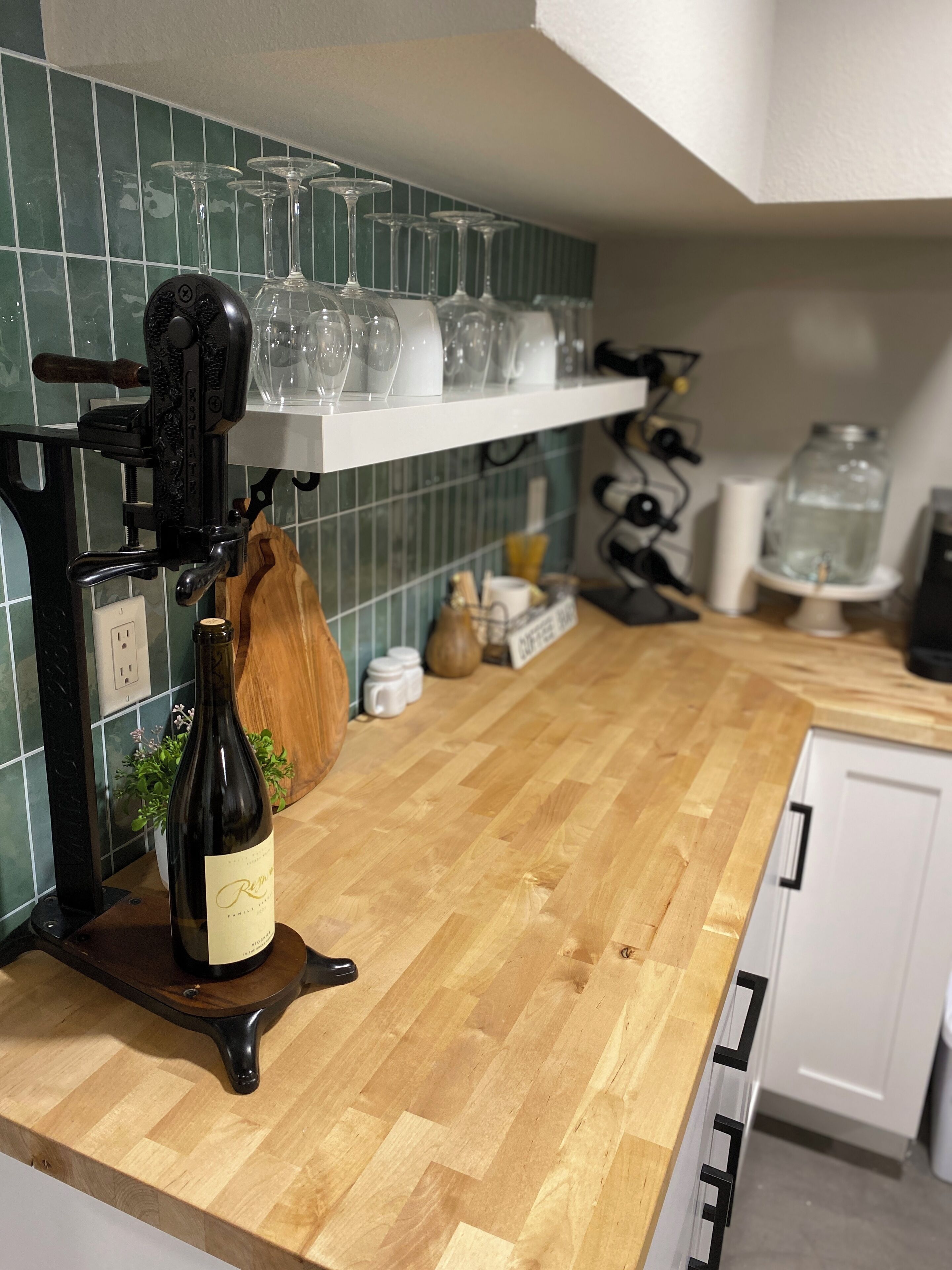 Una cocina con lagar de vino, copas de vino en una estantería y encimera de madera.