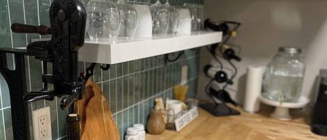 Una cocina con lagar de vino, copas de vino en una estantería y encimera de madera.