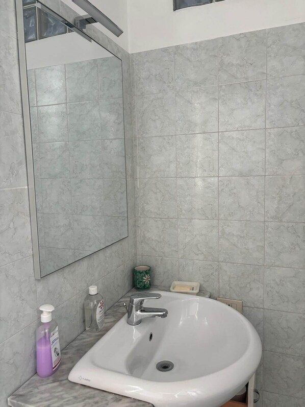 A bathroom with a white sink, a mirror, and a green soap dish. - Spacious apartment with park view in Conca d'oro (Roma)