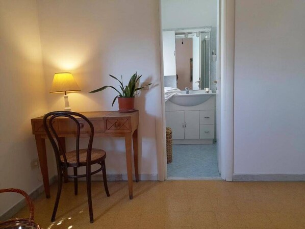 A room with a wooden desk, a chair, a potted plant, and a lamp.