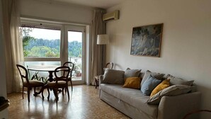 Una sala de estar con un sofá, una mesa de comedor con sillas y un cuadro en la pared.