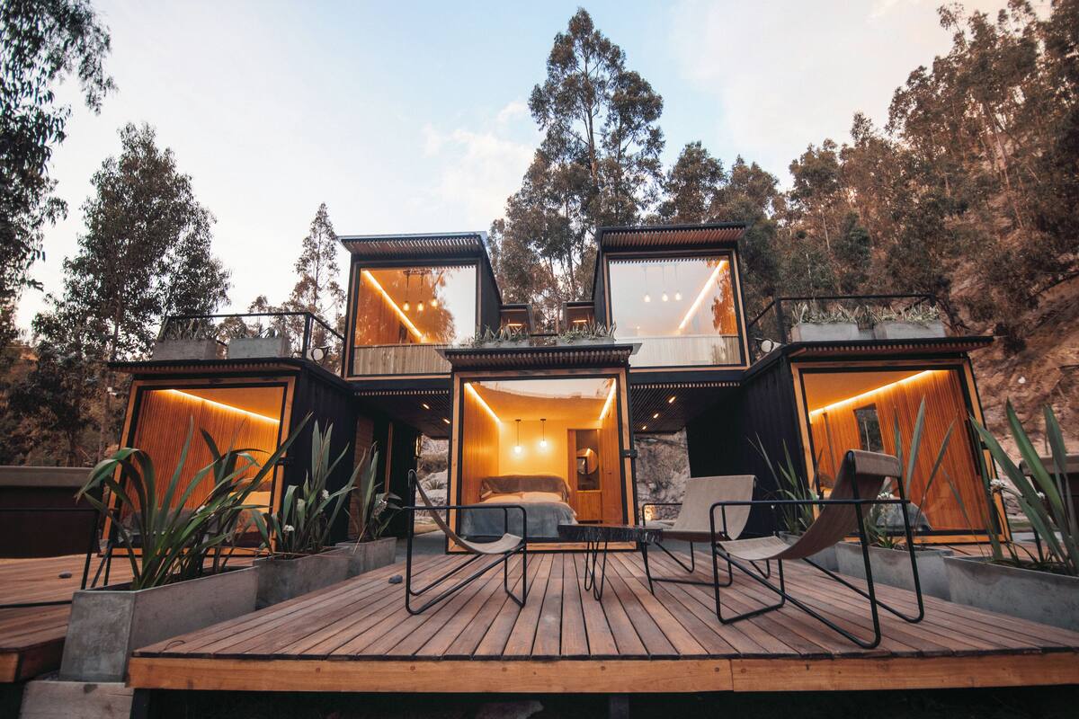 Una cabaña moderna de varios niveles con terraza de madera y zona de estar al aire libre.